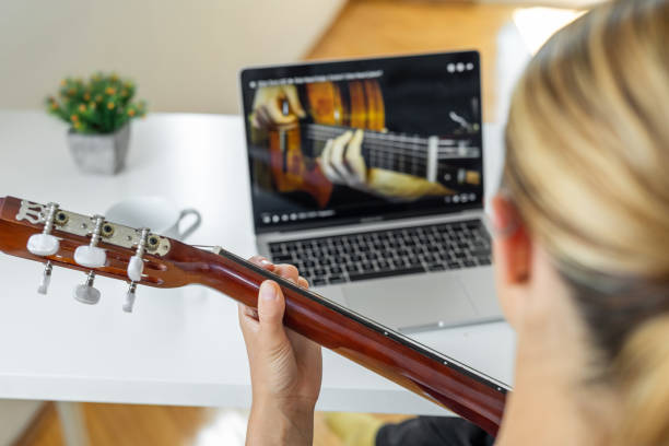 woman learning to play guitar at home